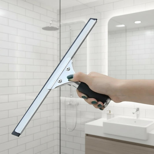 Hand holding a squeegee over a glass surface with a blurred indoor background